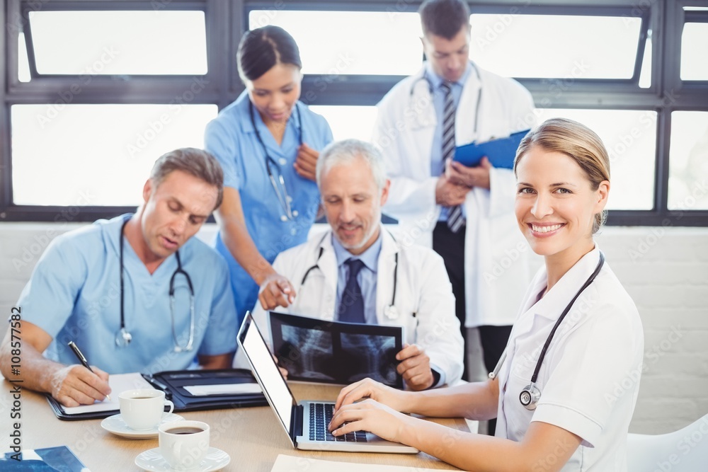 Portrait of female doctor using laptop in conference room