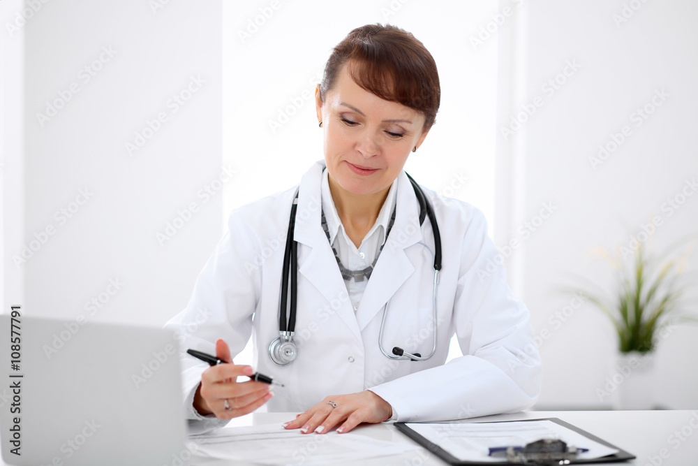 Woman doctor filling up medical history at the desk Woman doctor filling up medical history at the desk