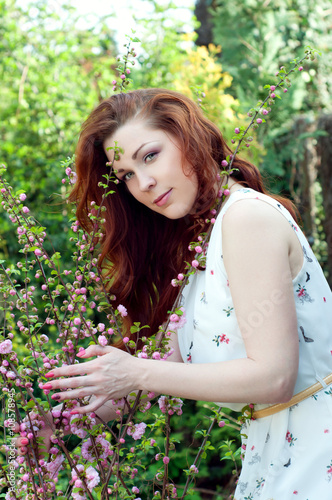 Redhead woman with green eyes in floral garden