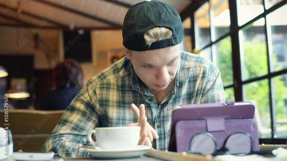Boy sitting in the cafe and having a videocall on tablet
Boy sitting in the cafe and having a videocall on tablet
