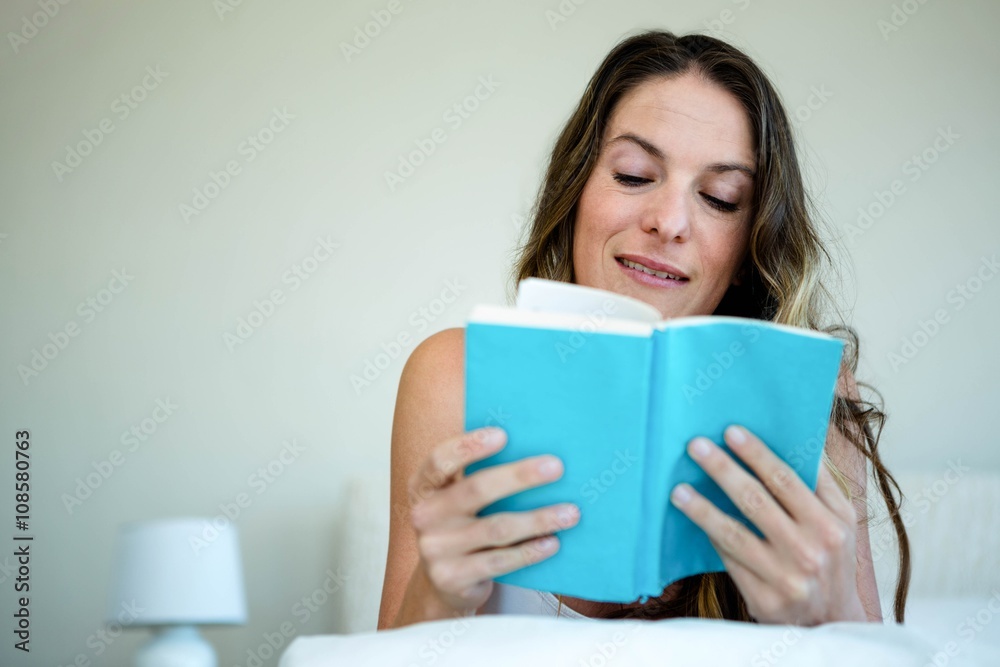 smiling woman reading a book in bed smiling woman reading a book in bed