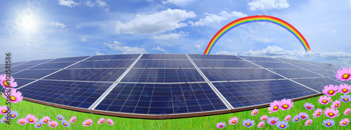 Solar panels on blue sky and rainbow with field of flowers.