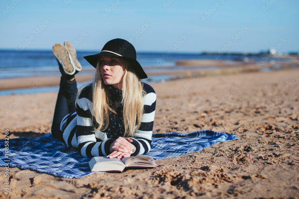girl reading a book lying on the beach