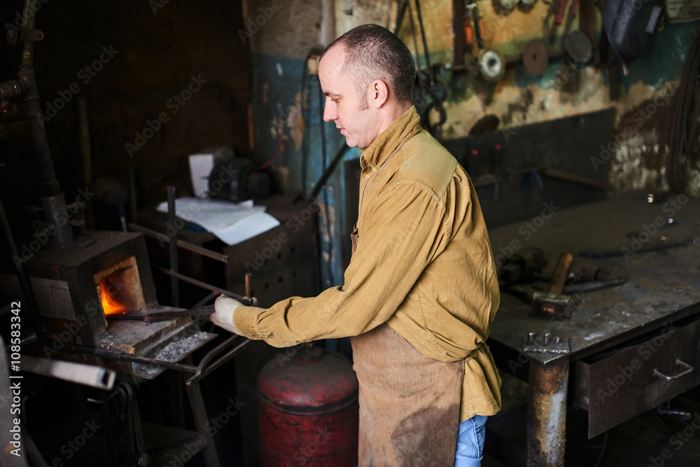 The blacksmith in the production process of metal products handmade in the workshop The blacksmith in the production process of metal products handmade in the workshop