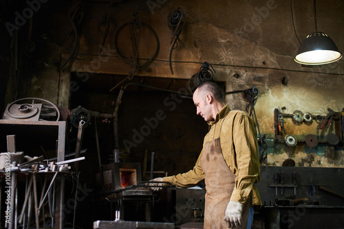 The blacksmith in the production process of metal products handmade in the workshop
