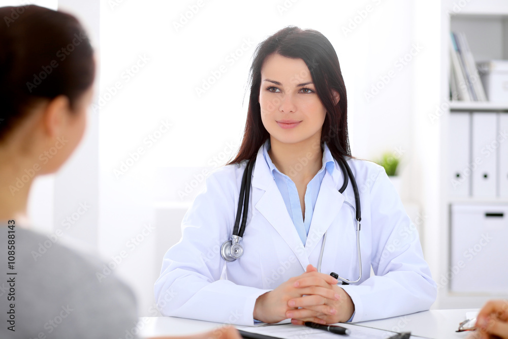 Brunette female doctor talking to patient in the hospital Brunette female doctor talking to patient in the hospital