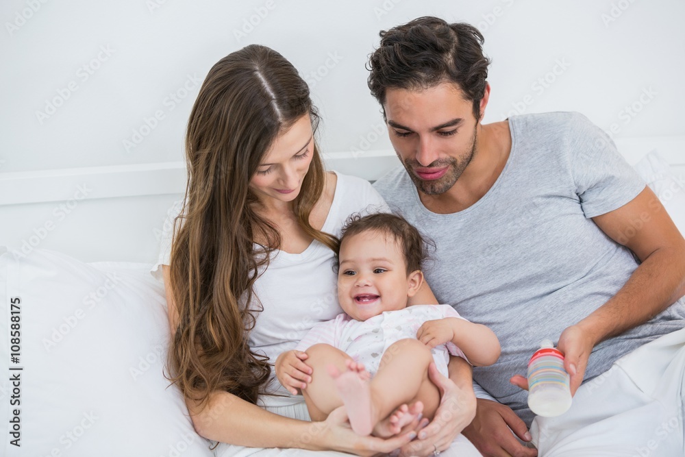 Young couple relaxing with baby on bed at Young couple relaxing with baby on bed at