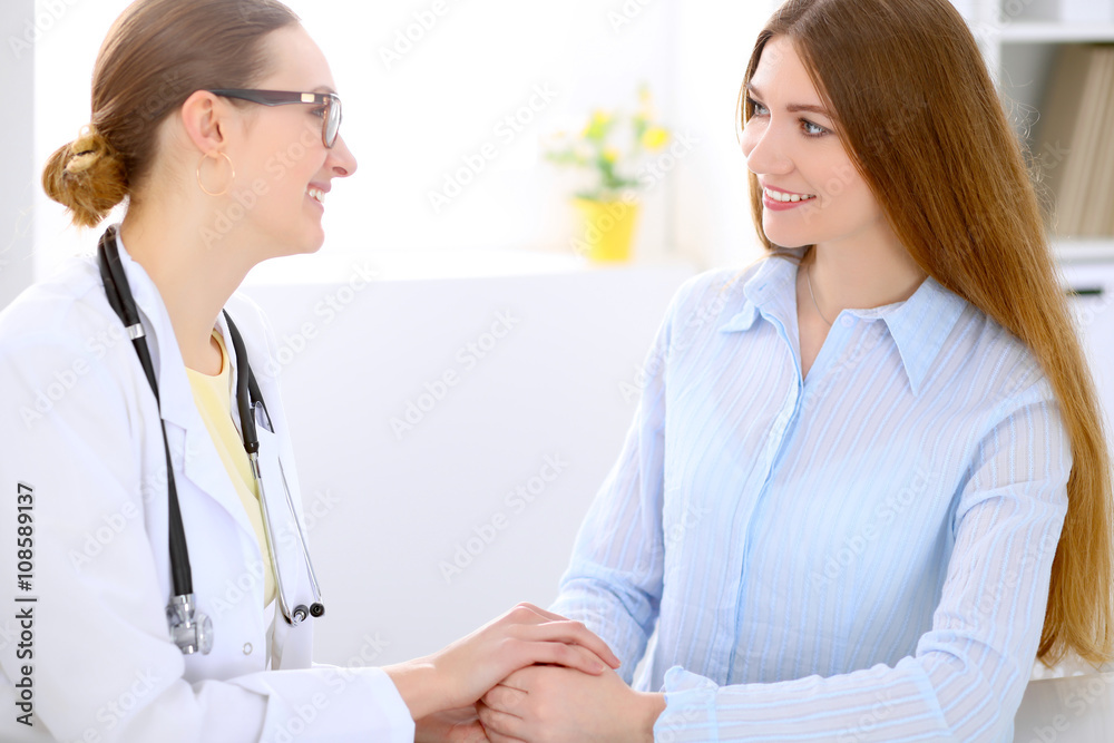 Doctor and patient sitting at the desk near window, sun shines Doctor and patient sitting at the desk near window, sun shines
