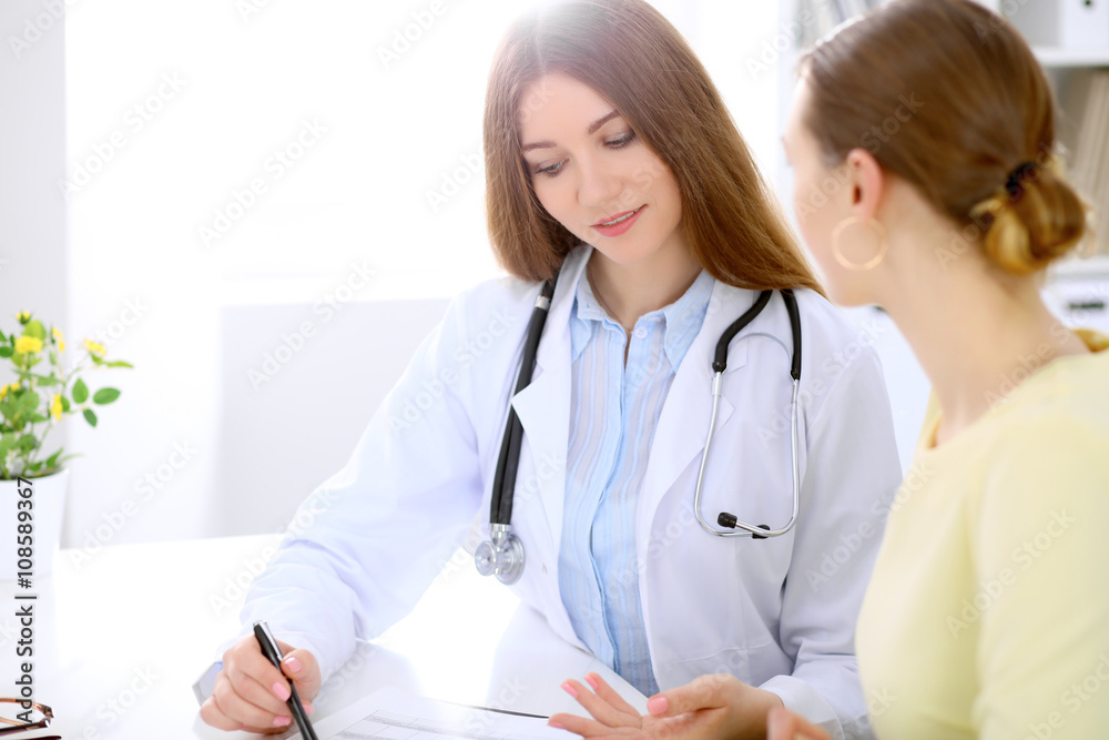 Doctor and patient sitting at the desk near window, sun shines Doctor and patient sitting at the desk near window, sun shines
