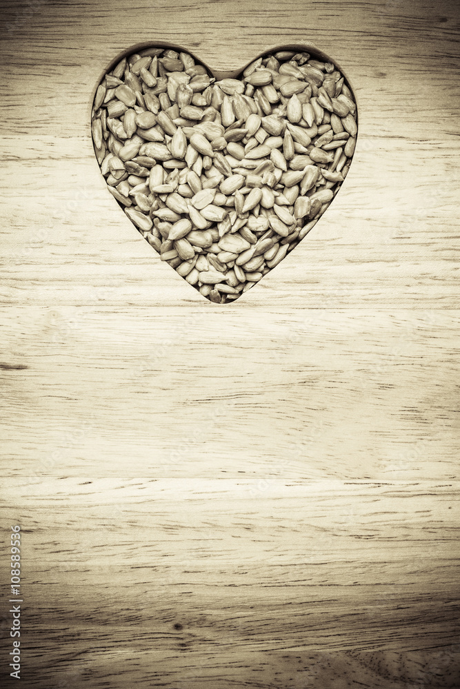 Obraz premium Heart shaped sunflower seeds on wood surface
