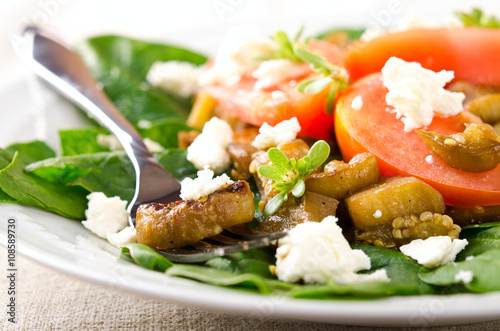 Eggplant salad with tomatoes, feta cheese, spinach and greens