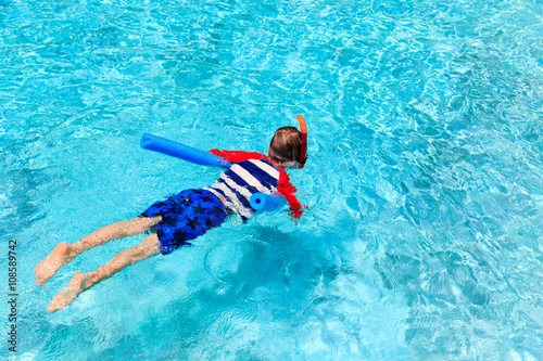 Little boy learns swimming alone with pool noodle