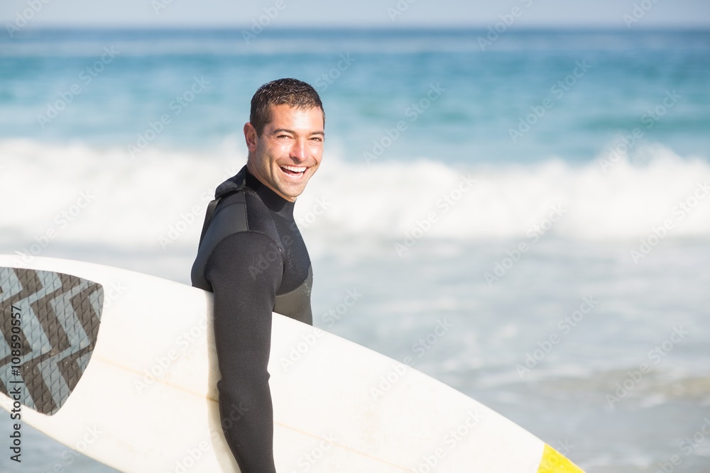 Portrait of happy man holding a surfboard on the beach