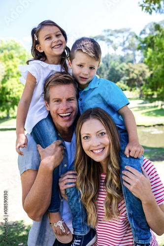 Happy parents carrying their kids on the shoulder in the park