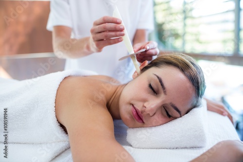 Woman receiving ear candle treatment