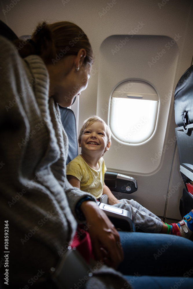 Mother and son talking and laughing on board of plane