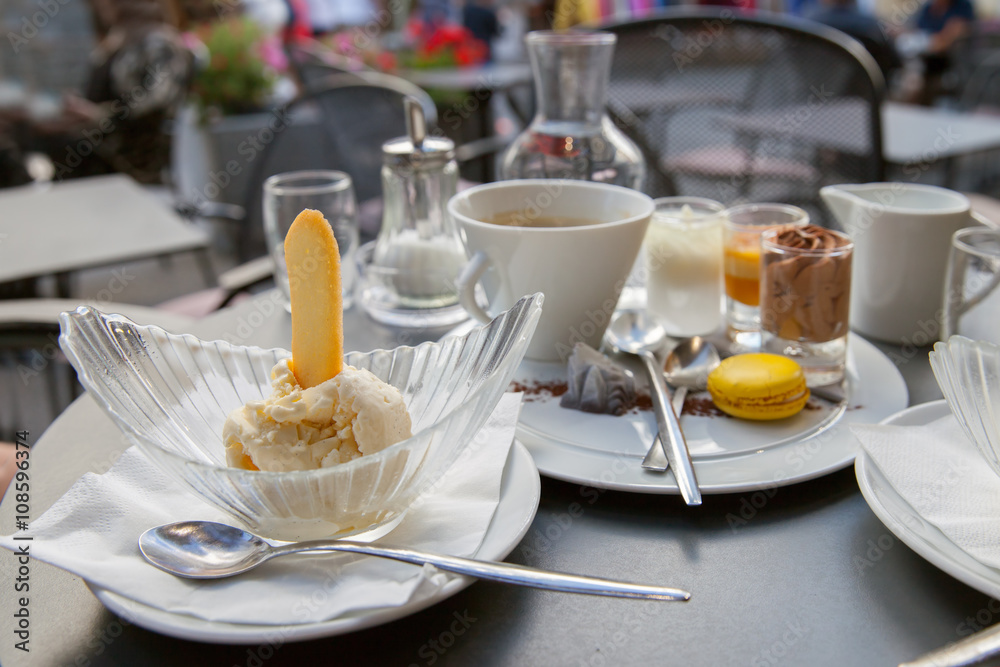 Vanilla ice cream with cookie and cup of coffee are on the table of street cafe Vanilla ice cream with cookie and cup of coffee are on the table of street cafe