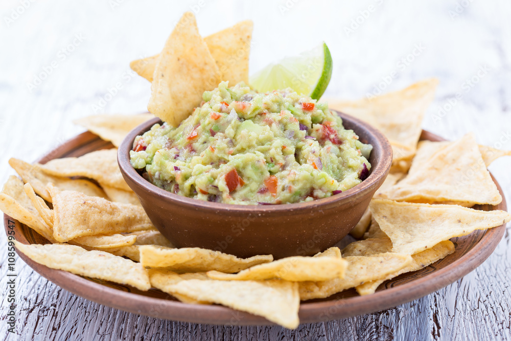 Homemade guacamole sauce and corn chips in ceramic bowl Homemade guacamole sauce and corn chips in ceramic bowl
