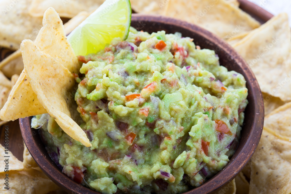 Homemade guacamole sauce and corn chips in ceramic bowl