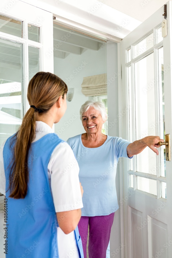 Smiling senior woman standing with nurse by door Smiling senior woman standing with nurse by door