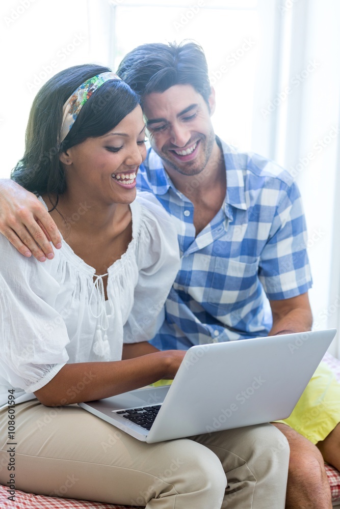 Young couple sitting on bed and using laptop Young couple sitting on bed and using laptop