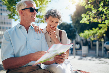 Senior couple using a city map for location in the town