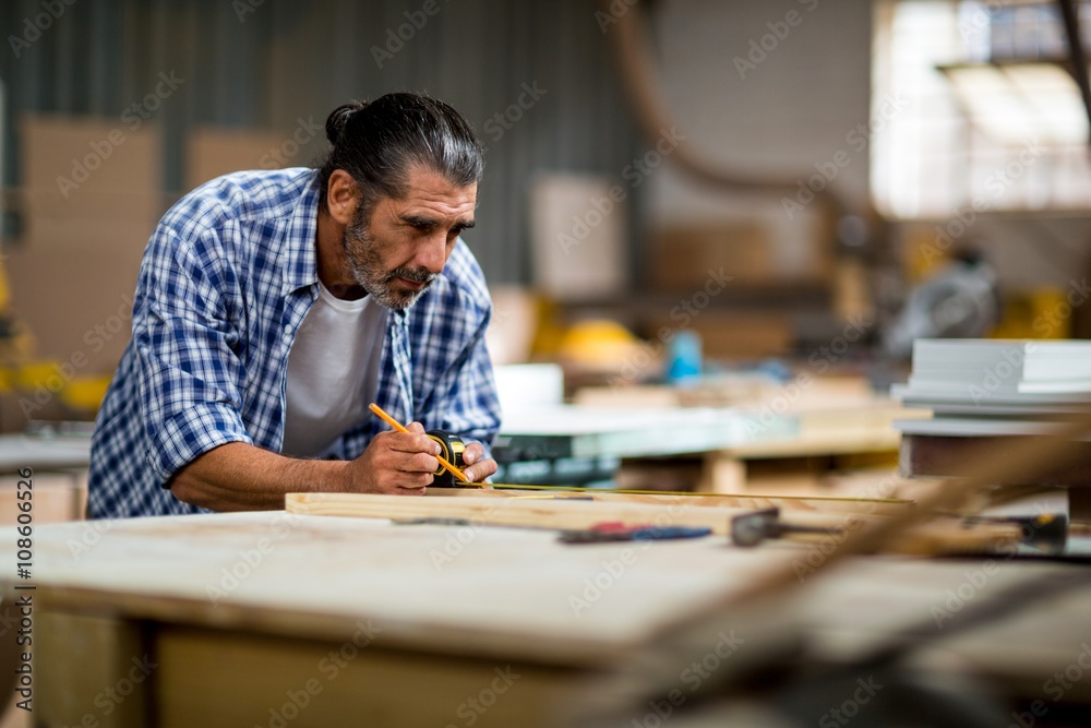 Carpenter marking on wooden plank with pencil Carpenter marking on wooden plank with pencil
