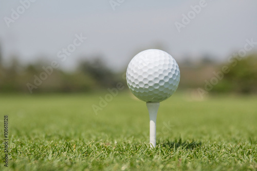 Golf ball on tee off zone with blurred golf course background. photo