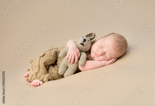 sweet newborn baby embracing toy-hare