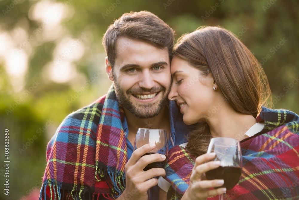 Naklejka premium Young couple with wine wrapped in blanket