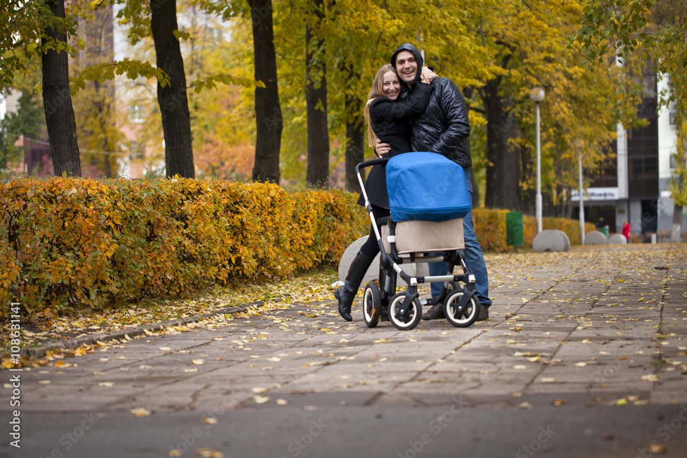 Young happy parents walking in autumn park