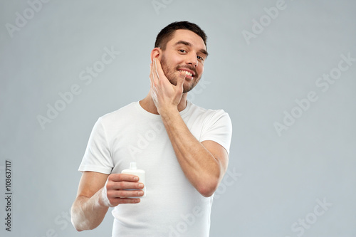 Photography happy young man applying cream or lotion to face