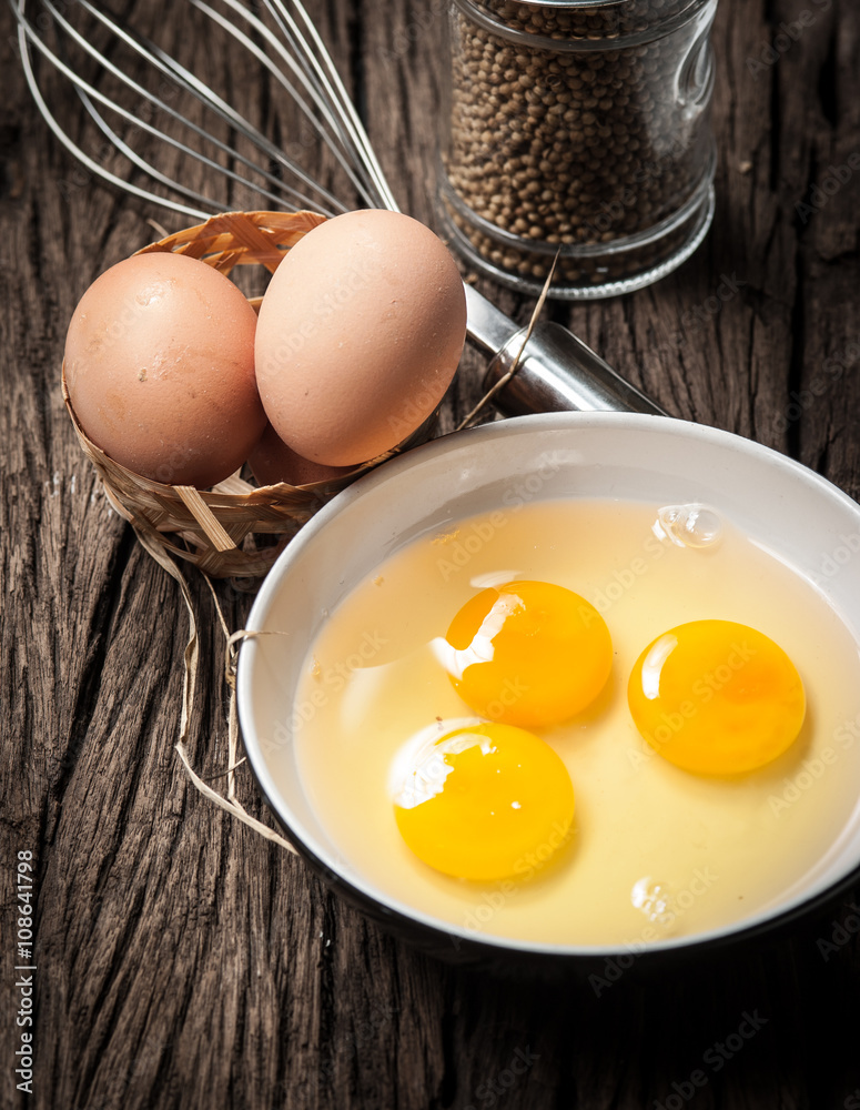 Eggs and whisk on wooden table Eggs and whisk on wooden table
