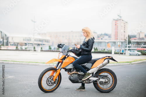 Young woman at motorcycle using mobile phone