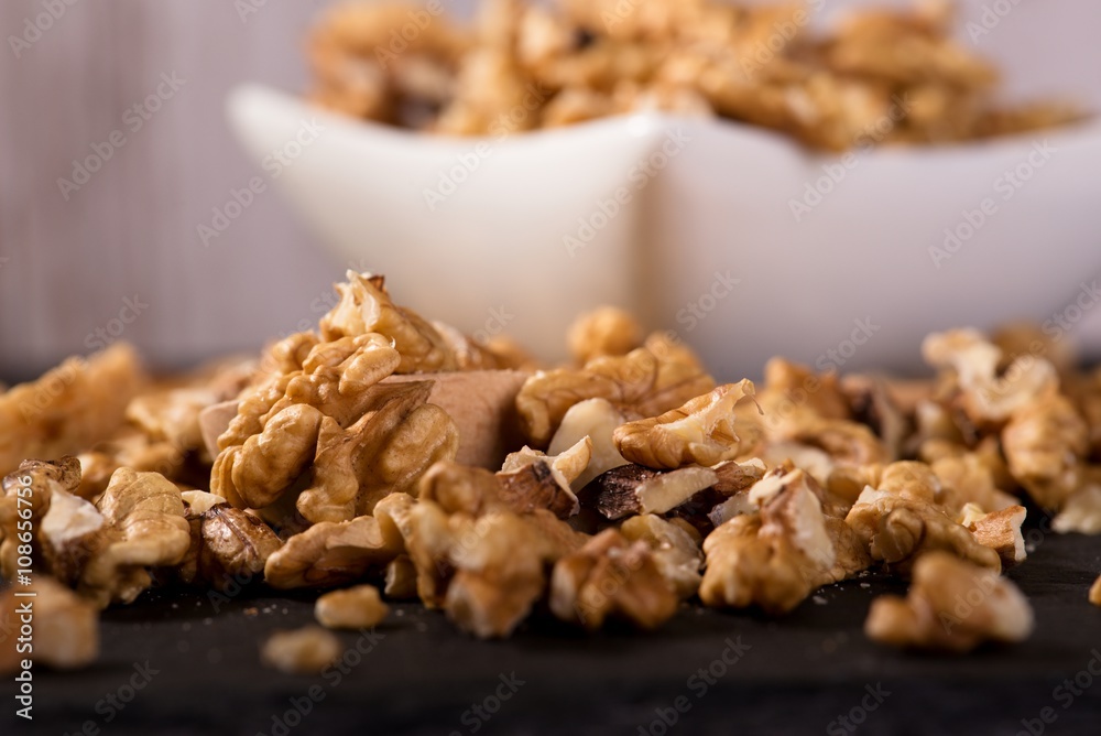 Spilled walnuts in front of square white bowl