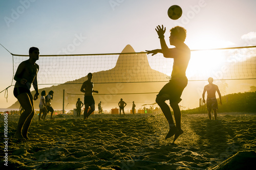 Silhouettes of Brazilians playing beach futevolei (footvolley), a sport combining football (soccer) and volleyball, at sunset on Ipanema Beach in Rio de Janeiro, Brazil