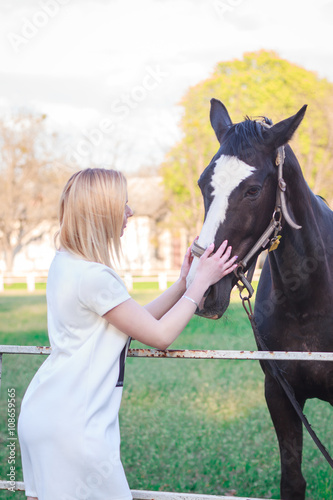 young woman petting a beautiful horse © nazarets
