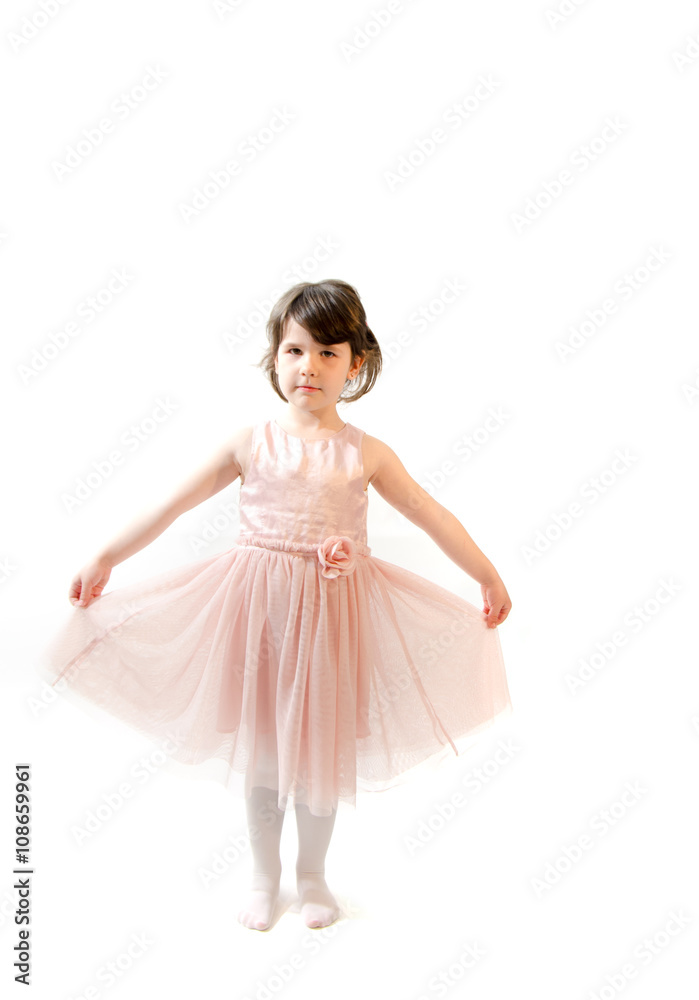 Sweet toddler girl in beautiful pink dress make gymnastics on wh