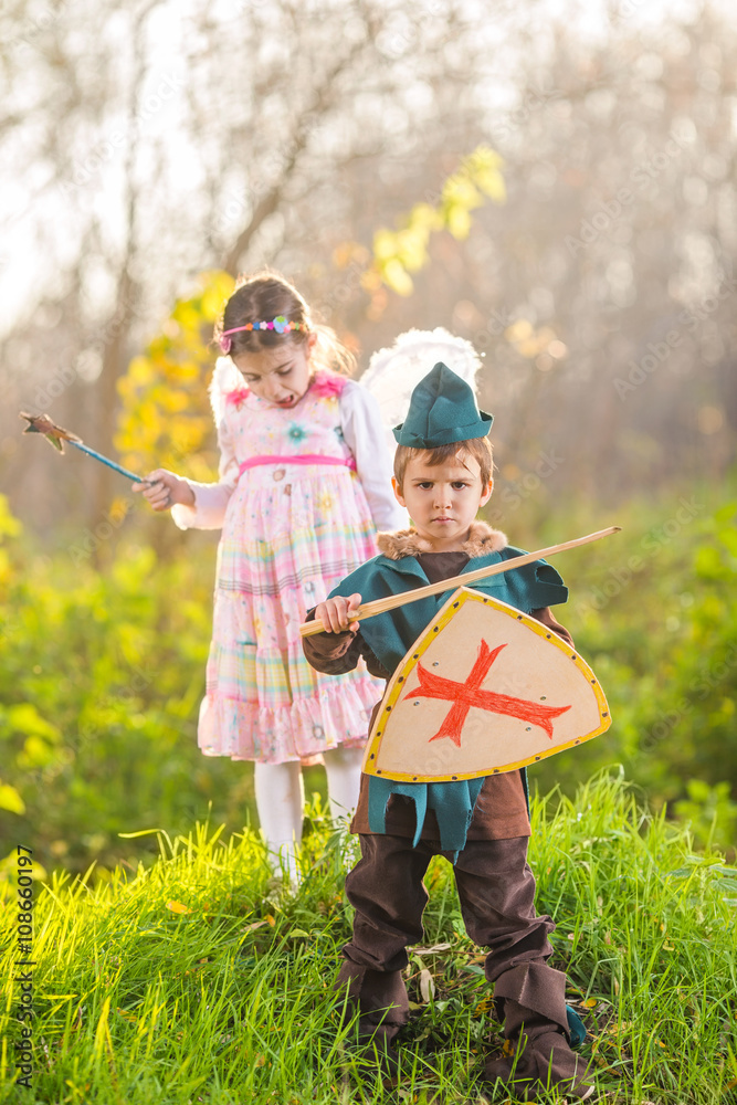 Φωτογραφία Cute little children dressed up as a knight and a fairy playing in the woods