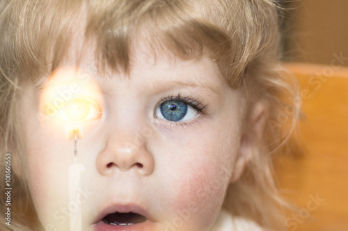 Little girl looking at a candle with her mouth wide open.