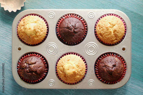 Homemade muffins in a baking trayon a wooden background. Top view