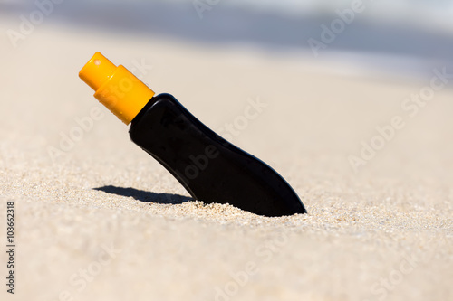 Sunscreen protection cream on white sand at the beach