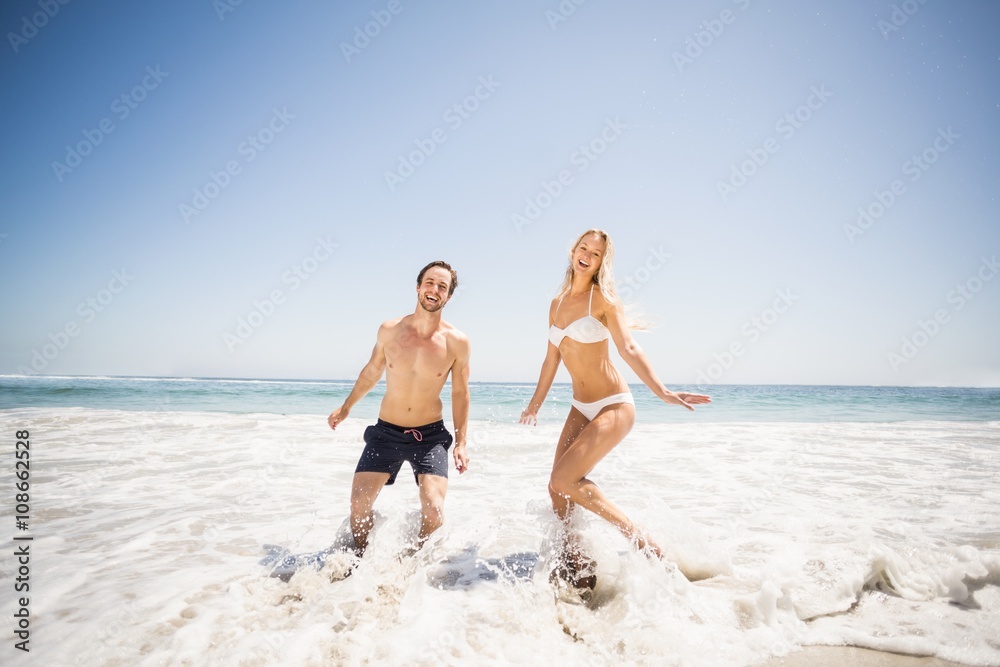 Happy couple having fun in water on shore