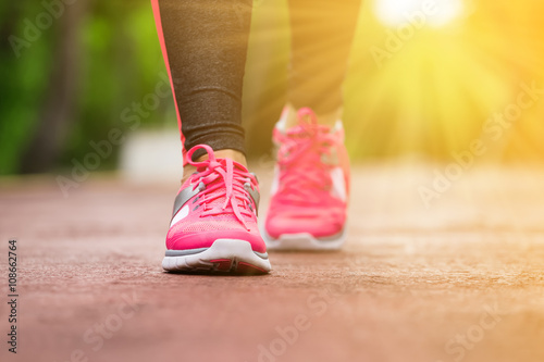 Fitness woman training and jogging in summer park, close up on running shoes in sunlight. Healthy lifestyle and sport concept 