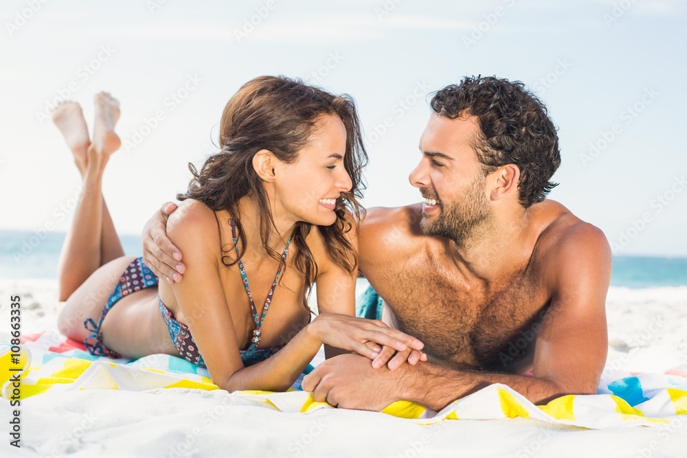 Fototapeta premium Couple lying on a towel at the beach