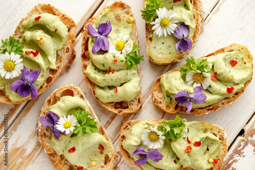 Stampa su tela Canapes with avocado paste and edible flowers