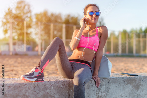 Athlete woman taking picture with smartphone camera, listining music, chatting on the beach summer holidays and vacation healthy lifestyle photo