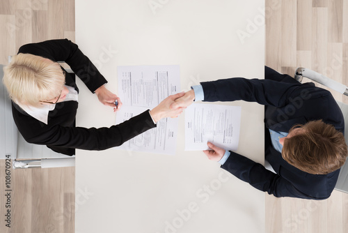 Businesspeople Shaking Hand At Desk