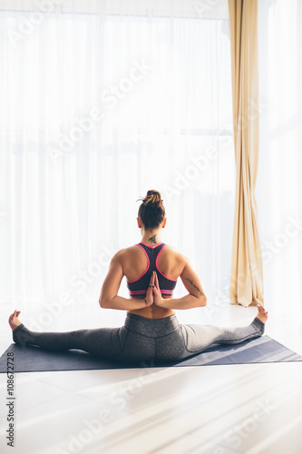 Hastapadasana. Beautiful yoga woman practice in a traning hall background. Yoga concept.