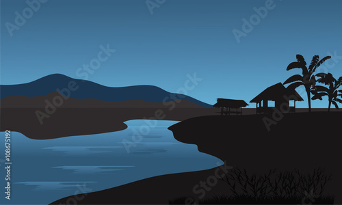 Silhouette of hut in riverbank